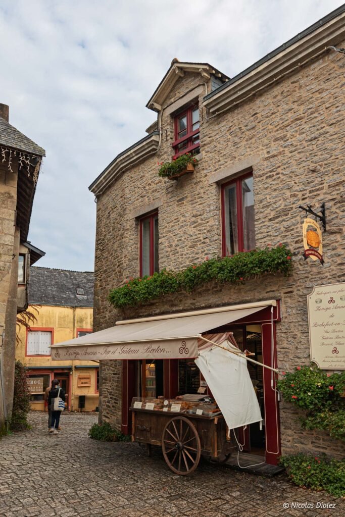 Boulangerie bretonne avec charrette de Kouign Amann sur rue pavée à Rochefort-en-Terre.