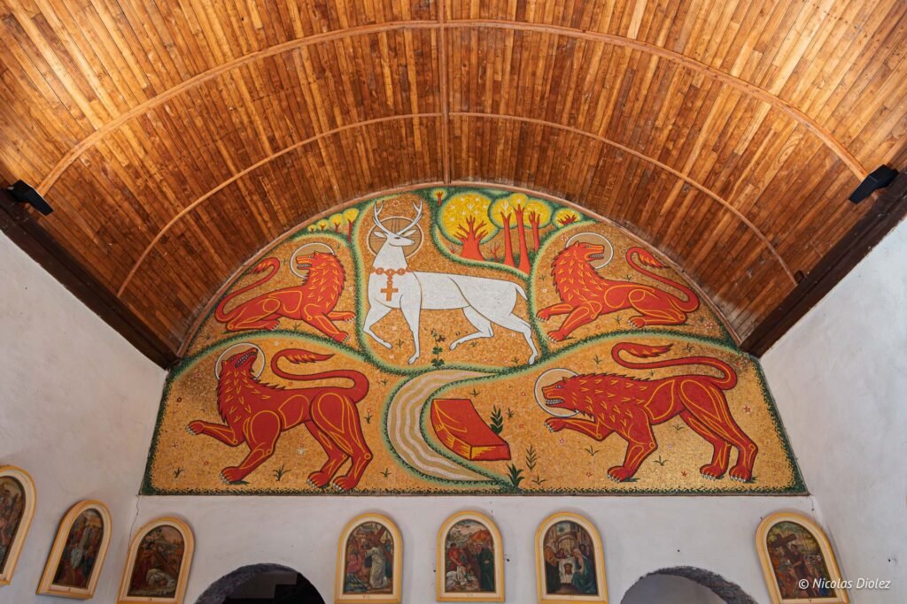 Mosaïque église du Graal: cerf blanc et quatre lions rouges sous plafond bois.