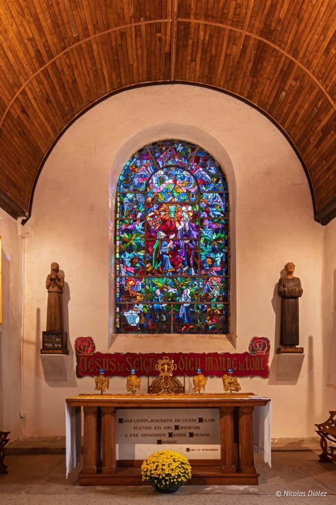 Intérieur église avec vitrail coloré, autel, statues Saint Onenne et Saint Judicaël.