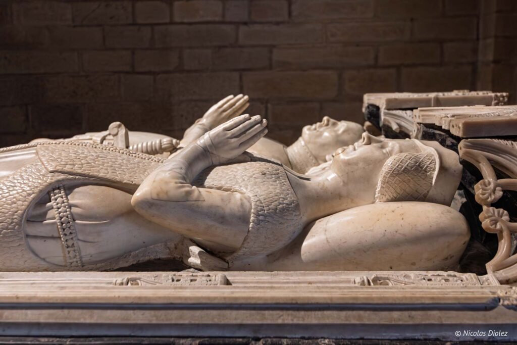 Détail de gisants en marbre d'un tombeau médiéval avec mains jointes.