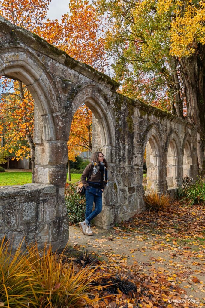 Femme appuyée contre un mur de ruines gothiques en automne, Josselin.
