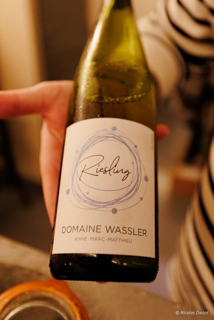Bouteille de Riesling Domaine Wassler Anne-Marc-Matthieu tenue à la main.