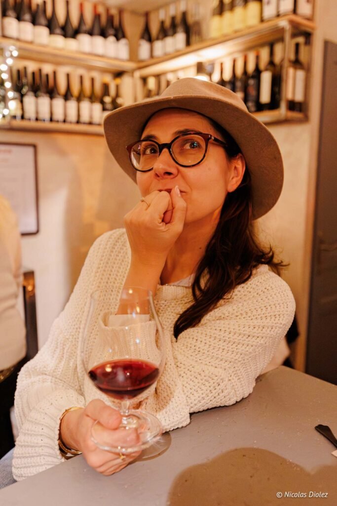 Femme avec chapeau et verre de vin rouge dans une cave à vin.