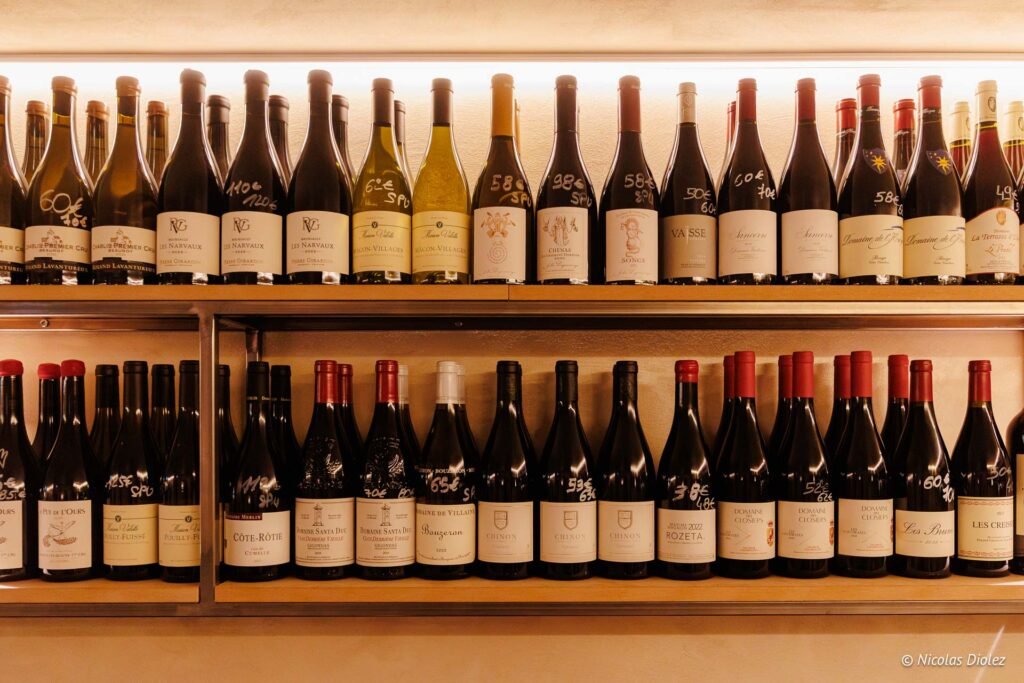 Bouteilles de vin exposées sur deux étagères avec prix manuscrits, La Cave Tire-Bouchon.