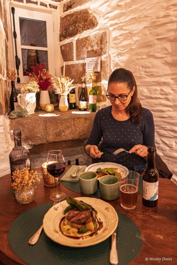 Femme mangeant un repas gastronomique dans un restaurant rustique en pierre.