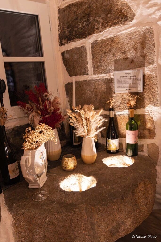 Décoration rustique avec vases, fleurs séchées, bouteilles de vin sur meule en pierre.