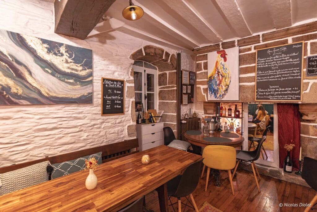 Intérieur rustique restaurant avec tables en bois et menus sur ardoise.