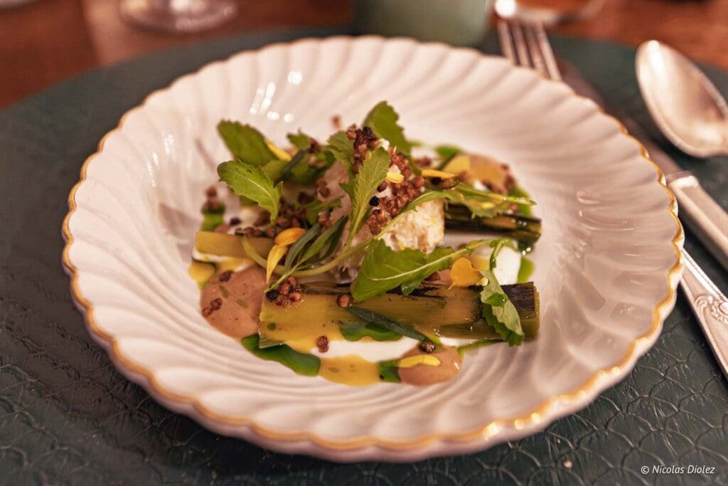 Poireaux grillés et morceaux de crabe garnis d'herbes fraîches et de graines croustillantes.
