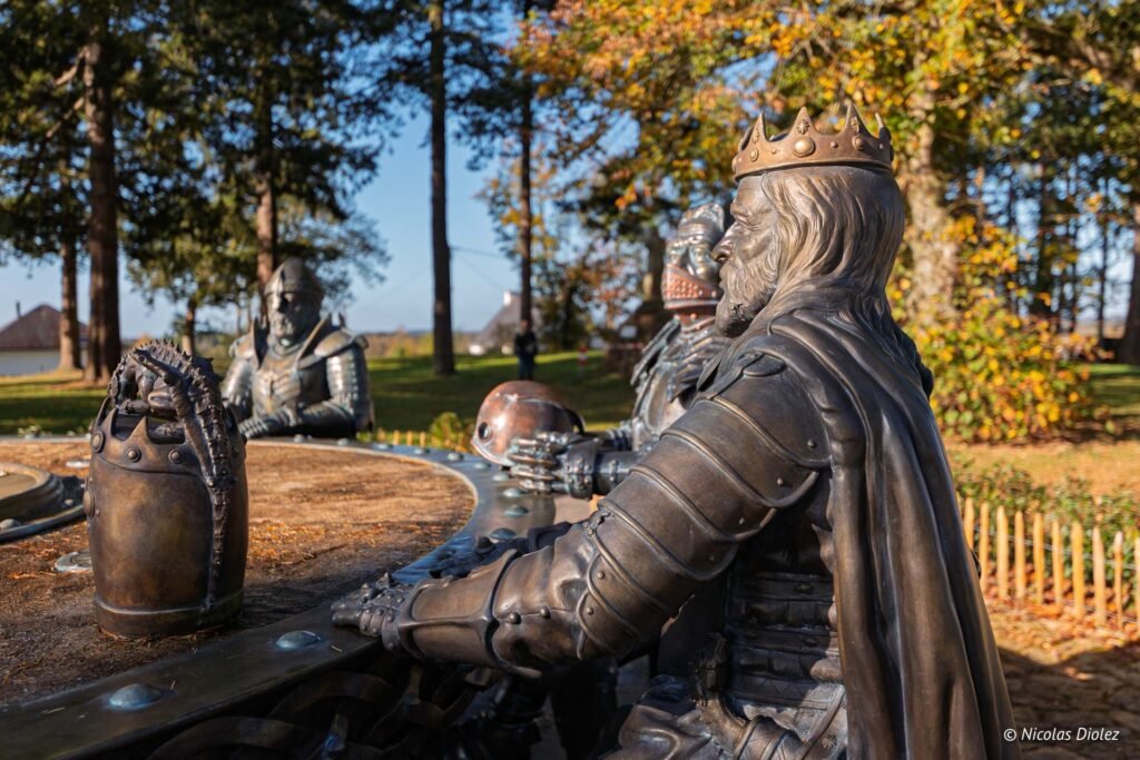 Statue d'un roi couronné en armure à la Table Ronde.
