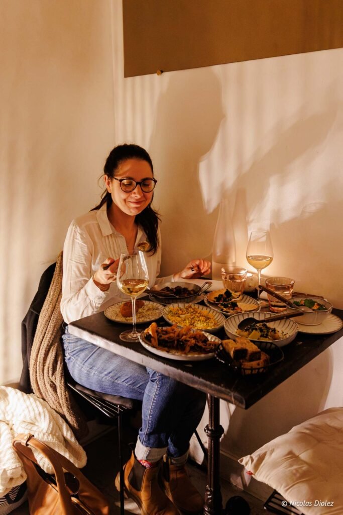 Femme dégustant des plats variés avec du vin blanc au restaurant Le Tire-Bouchon Rodier.