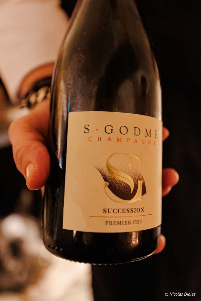Bouteille de Champagne S. Godmé Succession Premier Cru tenue à la main.