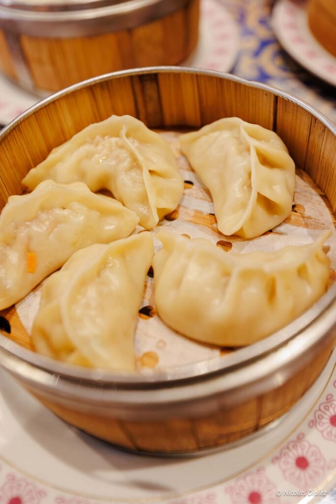 Raviolis vapeurs chinois (dim sum) servis dans un panier en bambou.