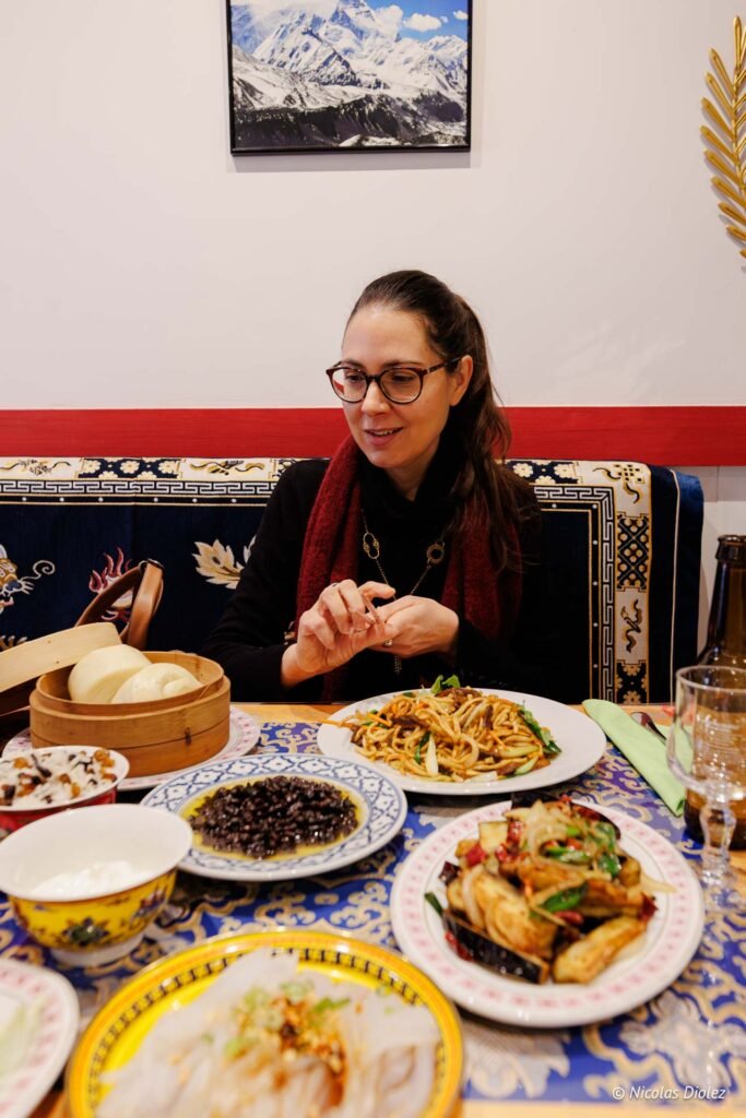 Femme souriante mangeant des plats tibétains avec Nicolas Diolez 2025.