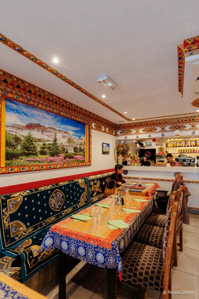 Intérieur restaurant tibétain décoré avec fresque du Palais de Potala et banquette brodée.