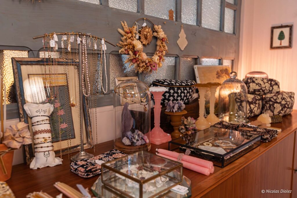 Bijoux artisanaux, objets décoratifs et couronnes de fleurs séchées sur un comptoir.