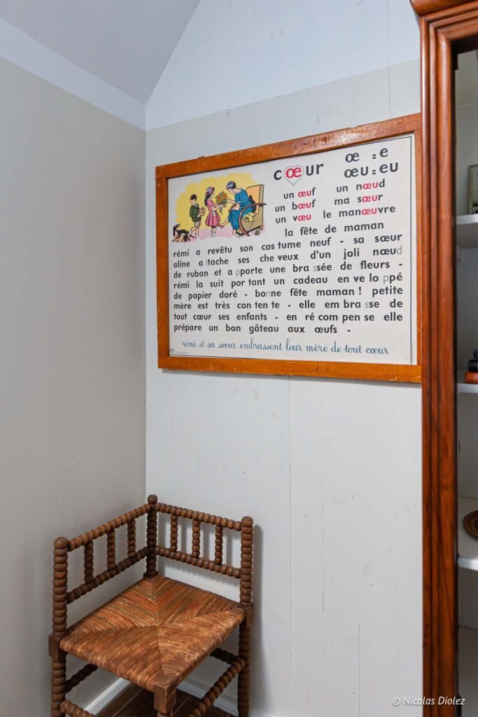 Tableau d'apprentissage ancien avec texte « Cœur » près d'une chaise d'angle en bois tourné.