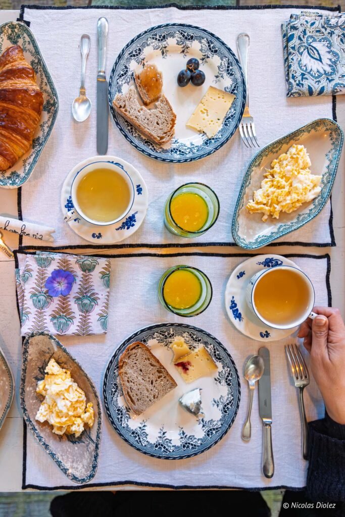 Petit déjeuner français avec croissant, œufs brouillés, thé et jus d'orange.