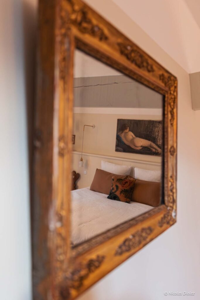 Reflet miroir doré chambre Maison Ogigi tableau nu coussins marron.