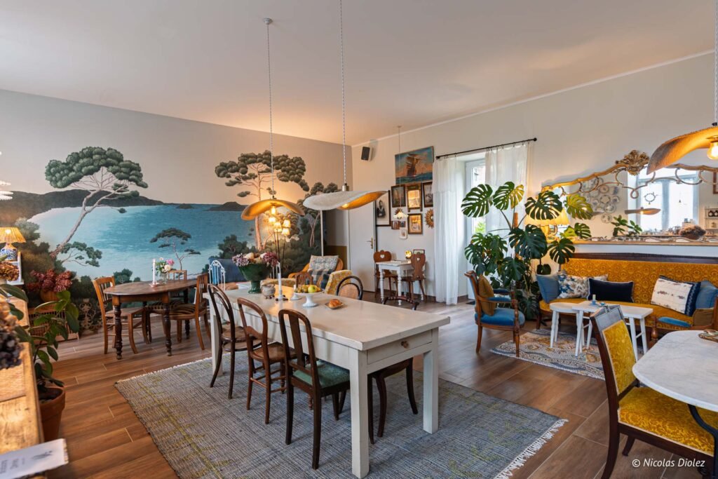 Salle à manger avec fresque murale paysage marin et mobilier vintage. Maison Ogigi.