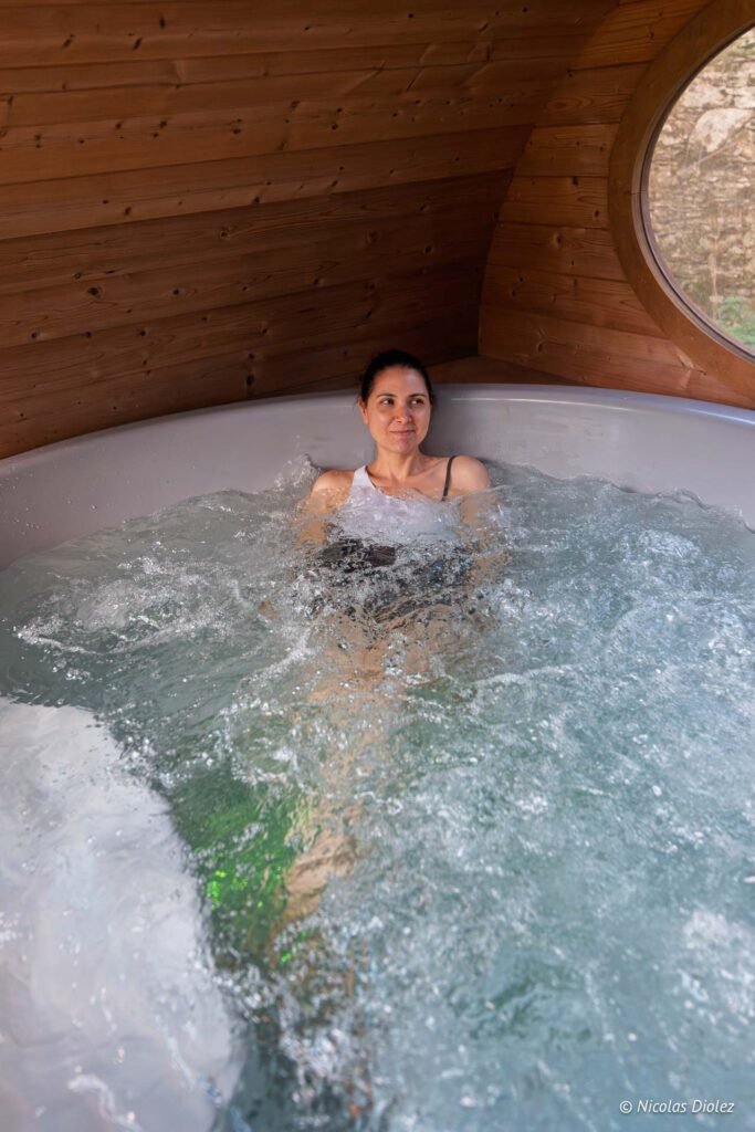 Femme souriante dans un jacuzzi intérieur en bois, bulles d'eau.