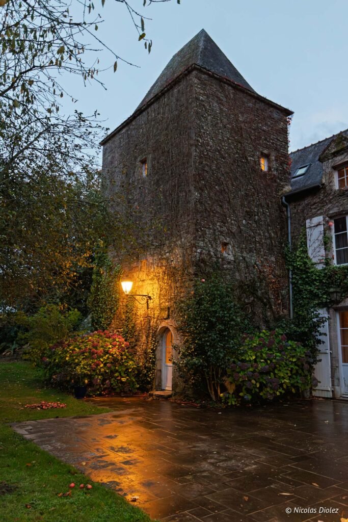 Tour du Manoir du Vau d'Arz, mur de pierre couvert de lierre, lumière du soir.