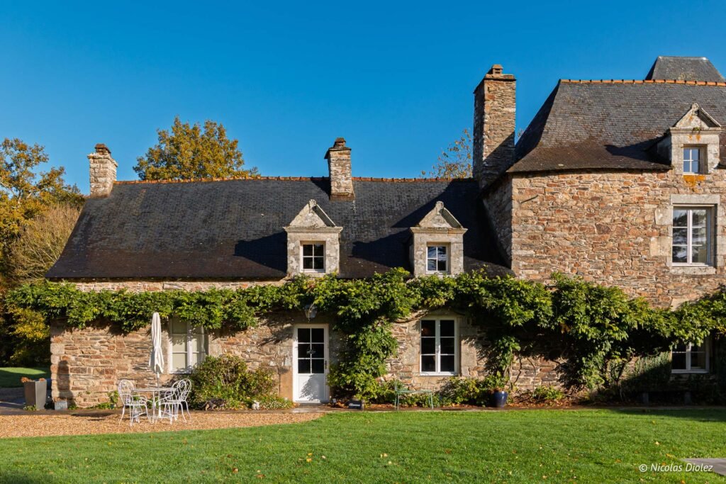 Manoir du Vau d'Arz en pierre avec toit en ardoise et végétation grimpante.