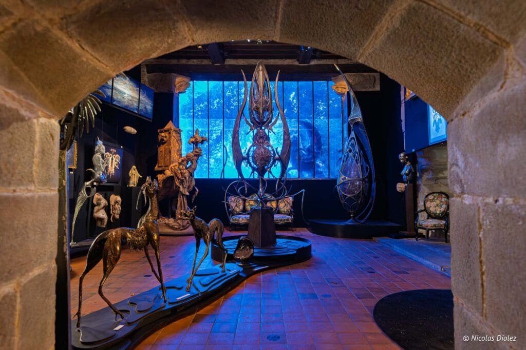 Sculptures fantastiques au Musée Naia de Rochefort-en-Terre sous éclairage bleu.