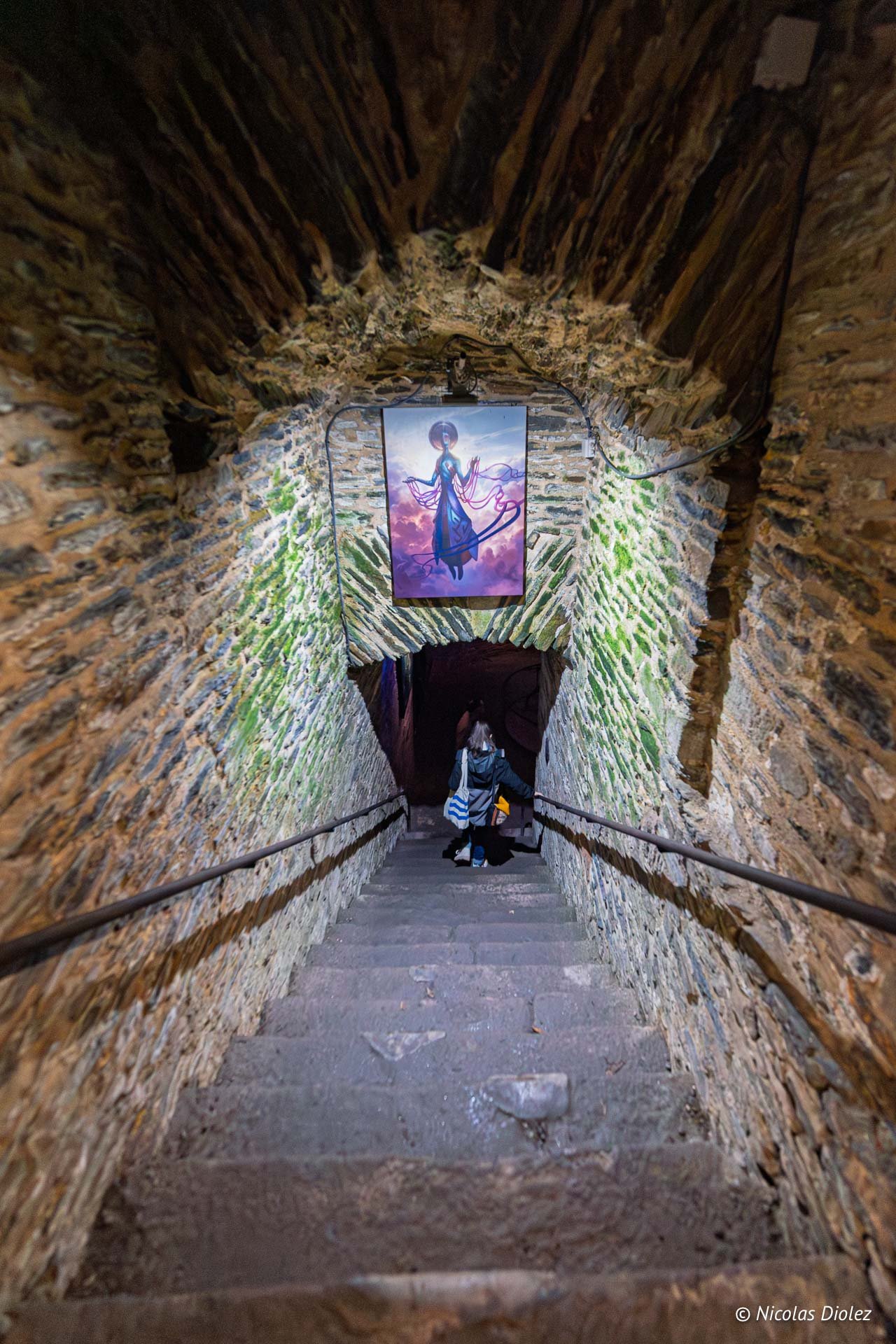 Escalier en pierre sombre au Musée Naia, Rochefort-en-Terre, avec peinture murale.