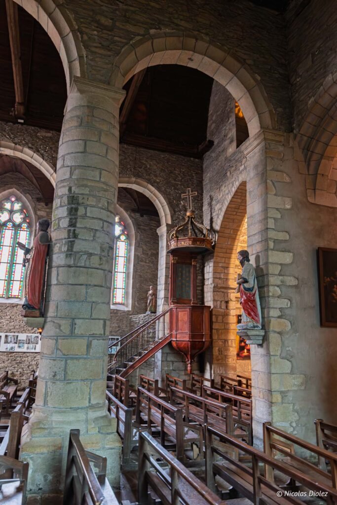 Intérieur église Rochefort-en-Terre: chaire en bois, statues et vitraux.
