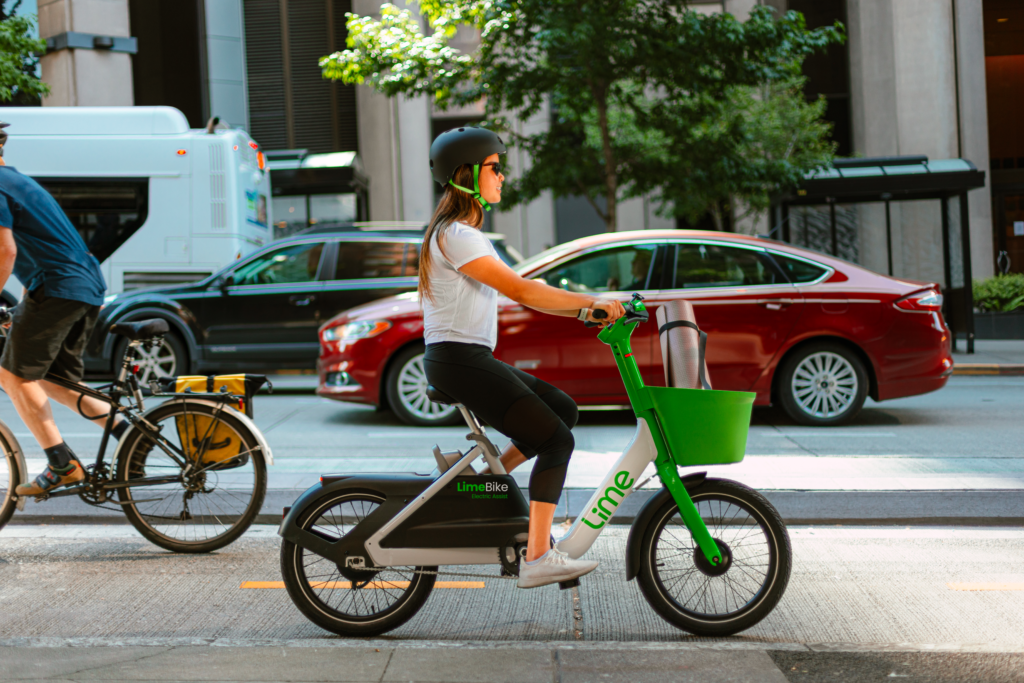 Femme portant un casque de protection à vélo électrique Lime dans une rue urbaine.