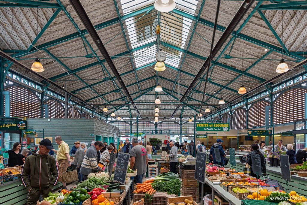 Clients achetant des fruits et légumes frais sous la halle couverte du marché de Châlons-en-Champagne.