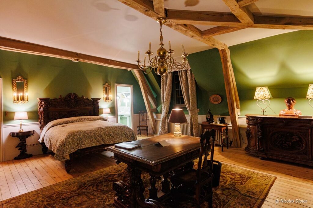 Chambre d'hôtes luxueuse au Château de la Rivière avec mobilier ancien et poutres apparentes.
