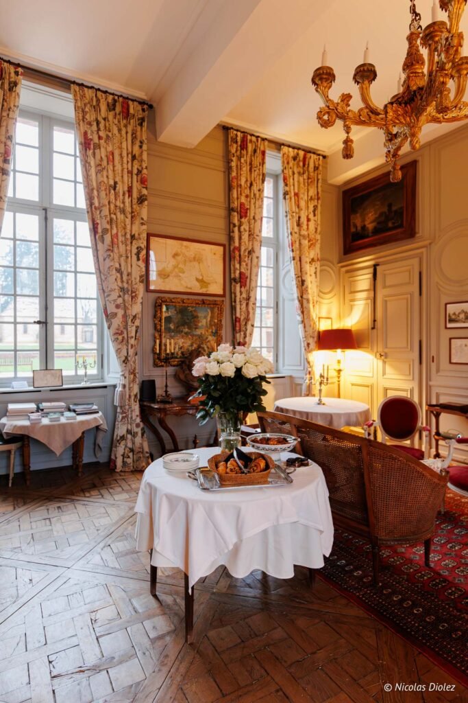 Salon élégant au Château de la Rivière avec petit-déjeuner et roses blanches.