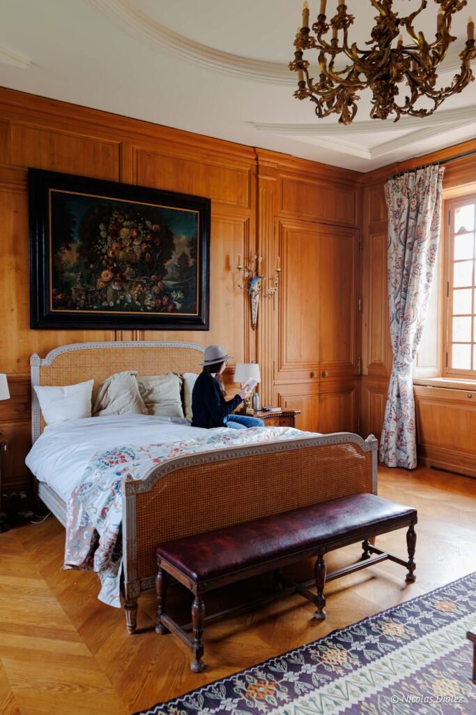 Chambre d'hôtes luxueuse au Château de la Rivière, femme lisant sur un lit.