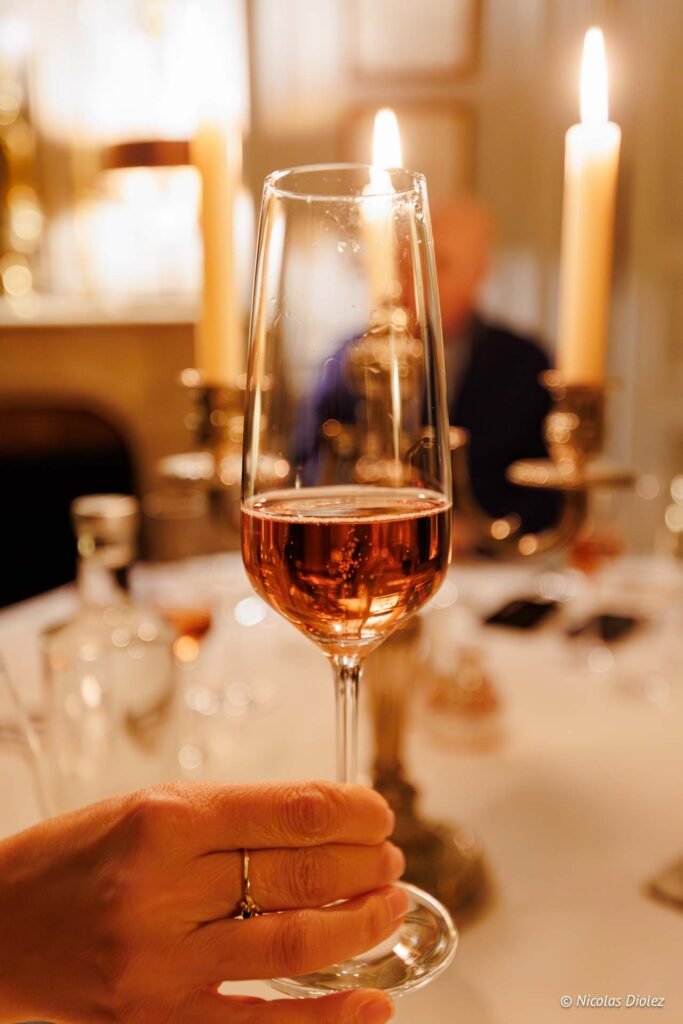 Verre de champagne rosé sur table illuminée par des bougies au Château de la Rivière.