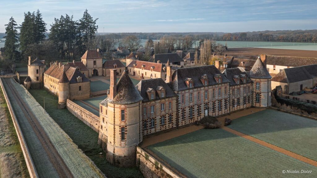 Vue aérienne du Château de la Rivière et ses dépendances avec douves et cour engazonnée.