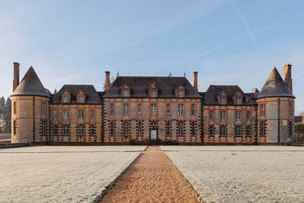 Façade du Château de la Rivière avec chemin givré et ciel bleu.