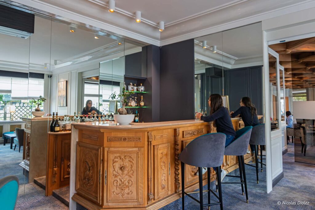 Client assis au comptoir en bois sculpté du bar de l'Hôtel d'Angleterre à Châlons-en-Champagne.