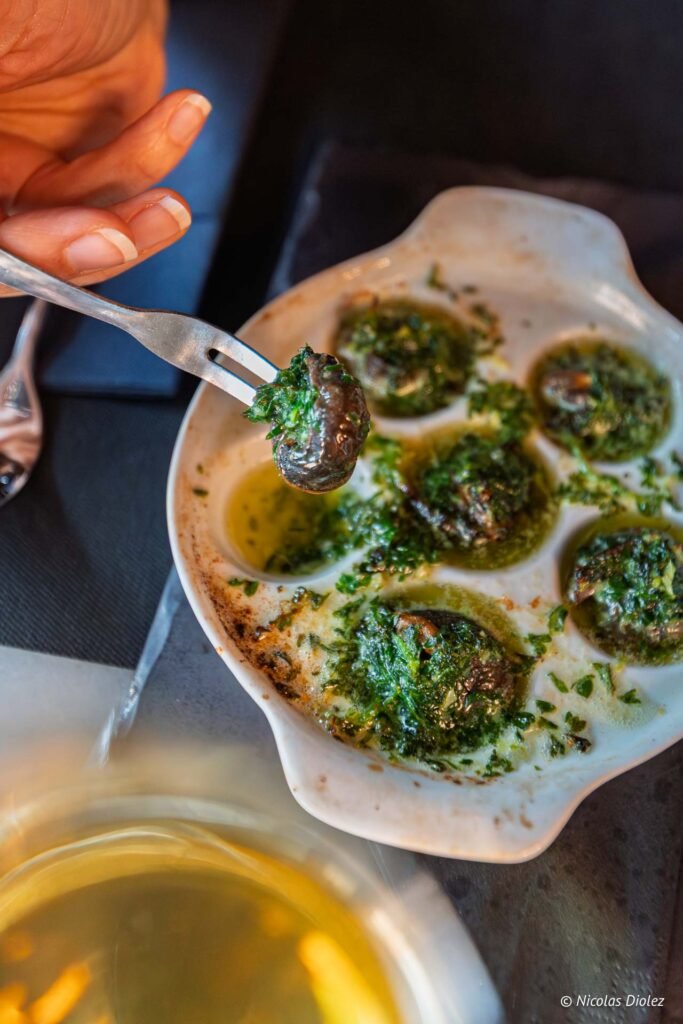 Escargots au beurre persillé servis dans une assiette au restaurant Le Comptoir de la Licorne à Châlons-en-Champagne.