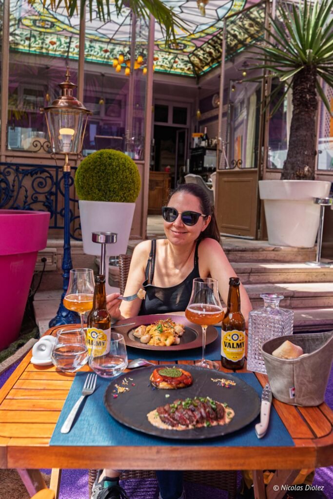 Femme dégustant un repas gastronomique accompagné de bières Valmy sur la terrasse du restaurant Les Caudalies à Châlons-en-Champagne.