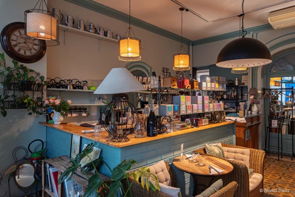 Intérieur chaleureux du salon de thé Marie-Caroline à Châlons-en-Champagne avec comptoir, étagères de thés et mobilier en rotin.