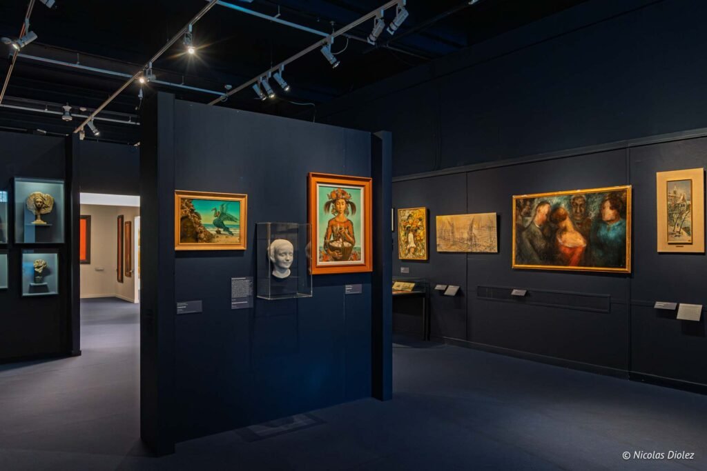 Exposition de peintures et sculptures au Musée des Beaux-Arts de Châlons-en-Champagne avec des œuvres sur des murs sombres.