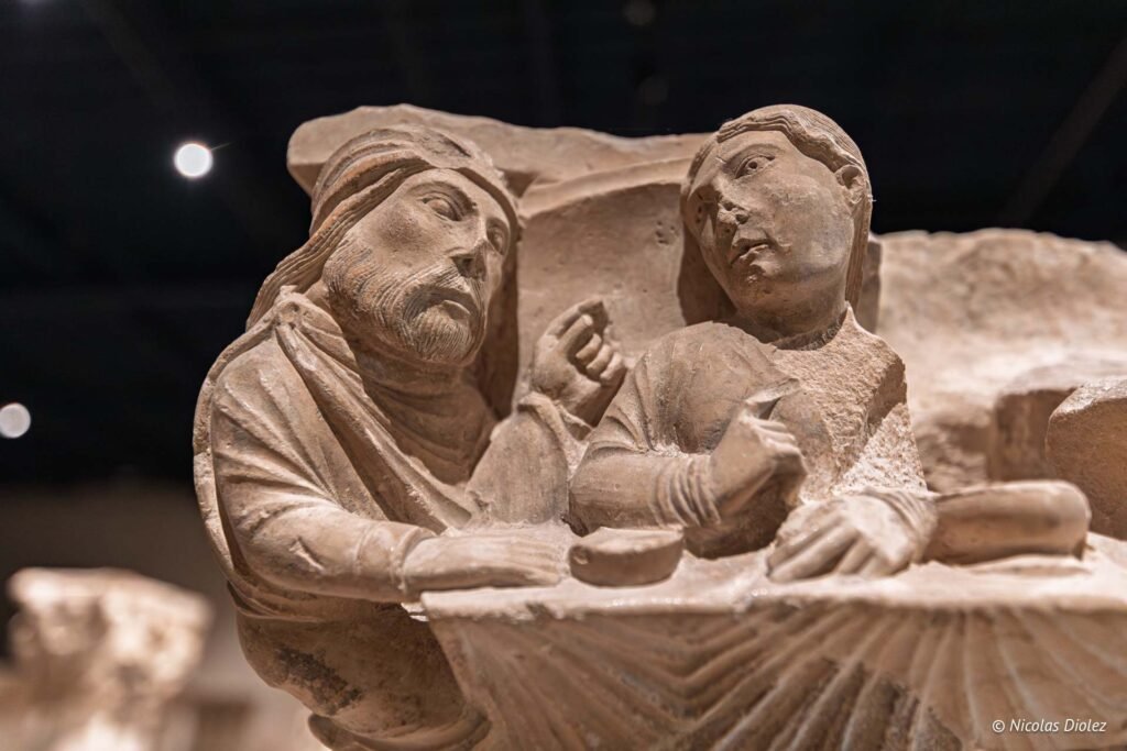 Sculpture médiévale en pierre représentant deux personnages attablés au Musée du Cloître de Châlons-en-Champagne.