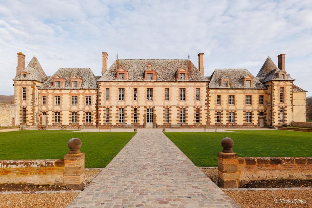 Façade du Château de la Rivière avec allée pavée et pelouse.