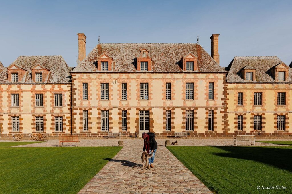 Visite Château de la Rivière avec femme et chien sur l'allée pavée.