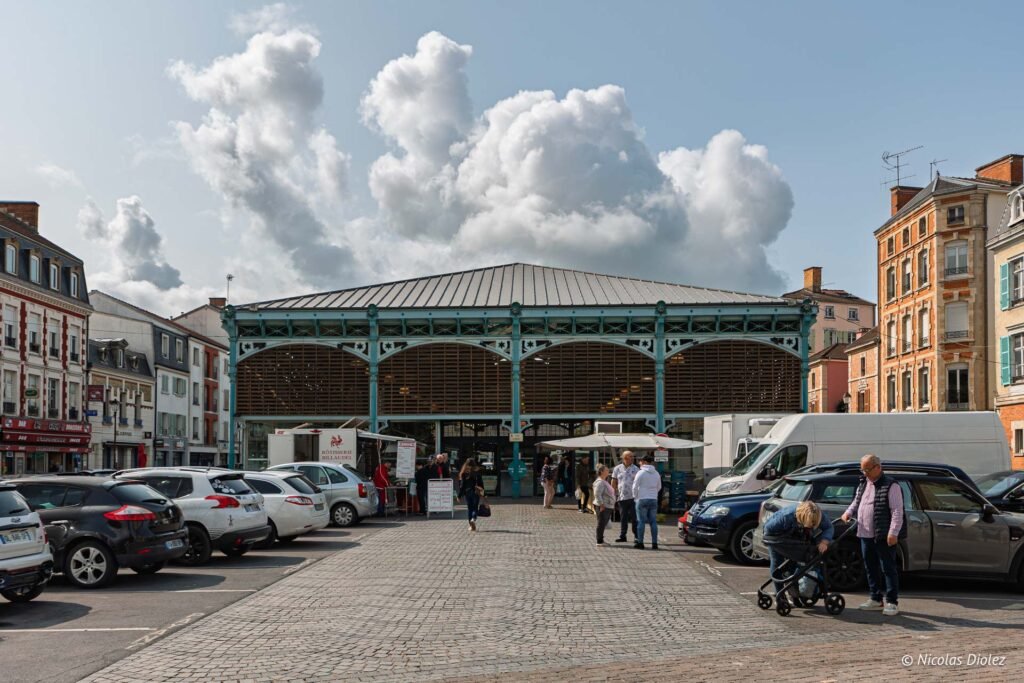 Personnes devant les halles du marché couvert de Châlons-en-Champagne avec voitures garées et stand de rôtisserie.