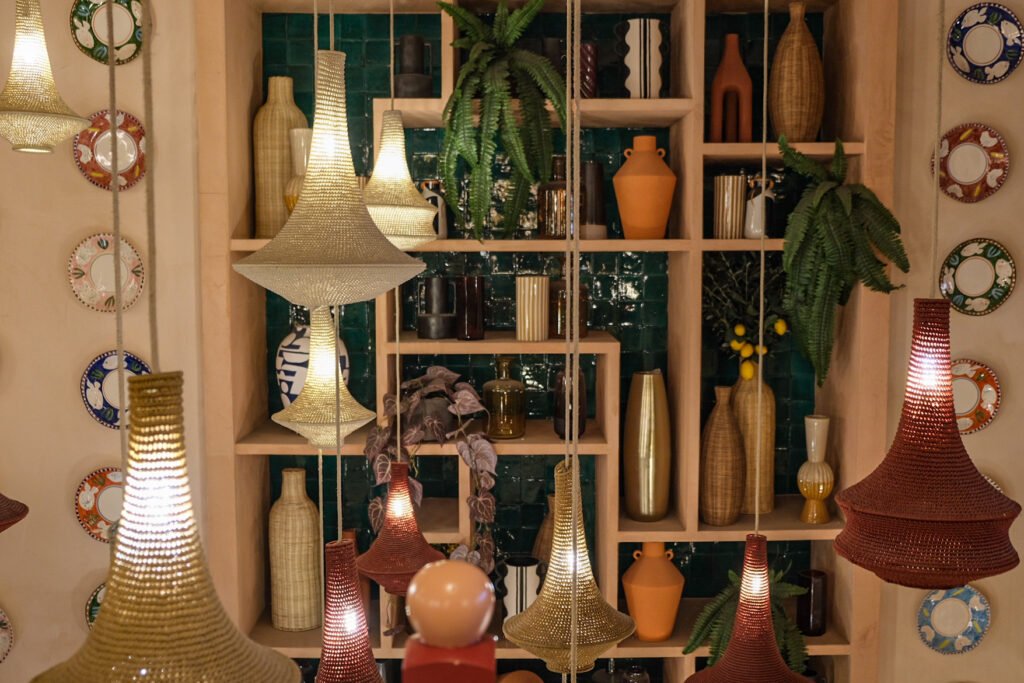 Wooden shelves decorated with vases, plants, and wall plates, illuminated by modern pendant lights at Noura Opéra restaurant.