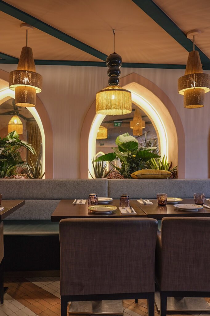 Elegant interior of Noura Opéra restaurant with set tables, comfortable benches, and warm lighting under decorative arches.