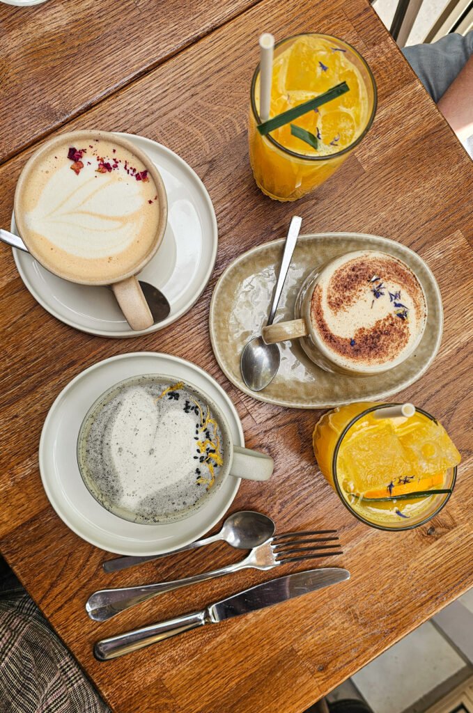 Sélection de boissons, lattes et jus frais servis sur une table en bois dans une pâtisserie.