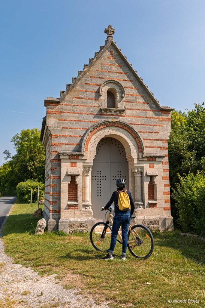 Cycliste devant la chapelle Saint-Gibrien près de Châlons-en-Champagne, avec l'inscription « St Gibrien priez pour nous ».